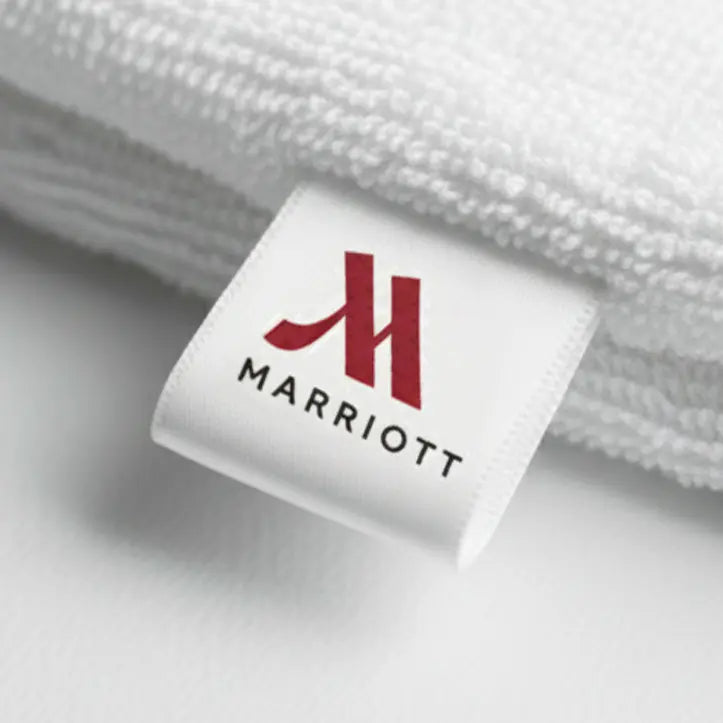 Custom fabric label attached to premium hotel linen towel for textile branding.