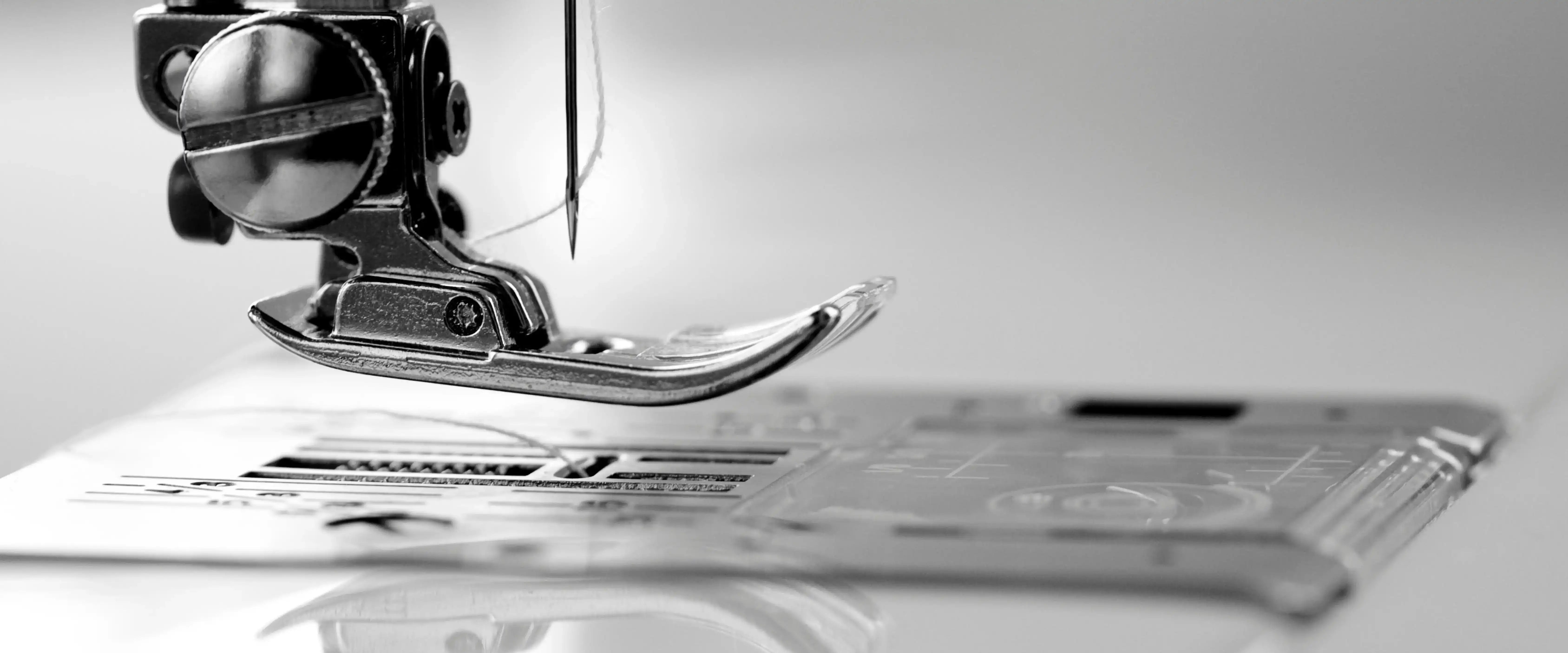 Close-up of sewing machine stitching fabric during hotel linen textile manufacturing process