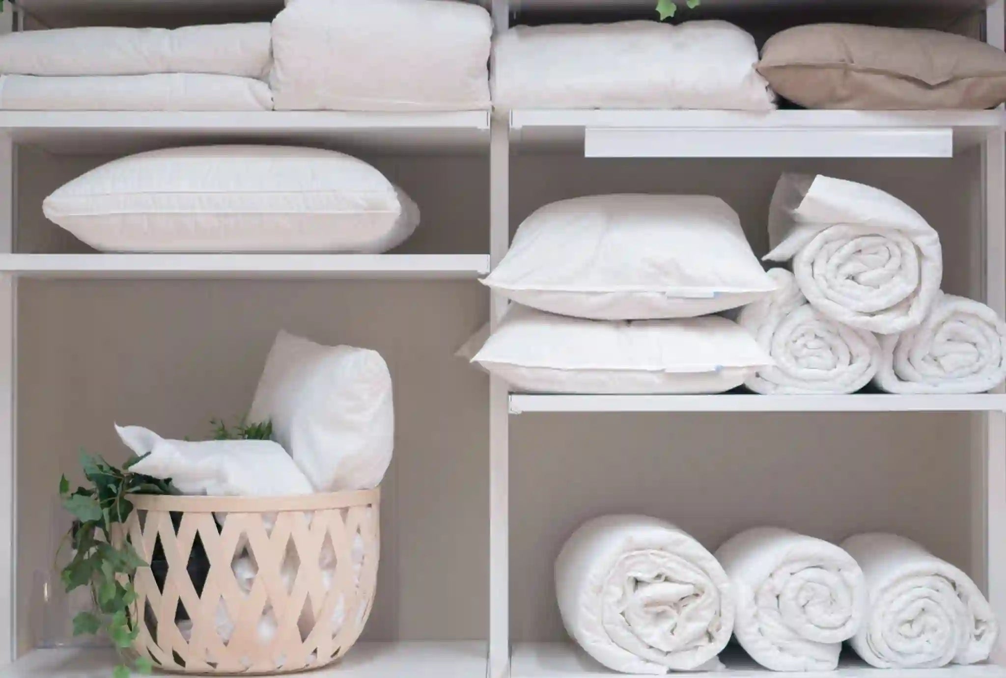 White pillows and folded bedding neatly stored on shelves