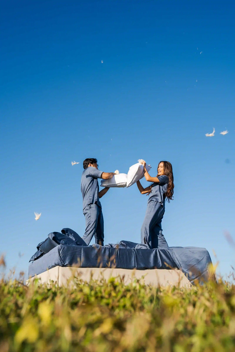 Couple enjoying a pillow fight on luxury bedding with premium pillows.