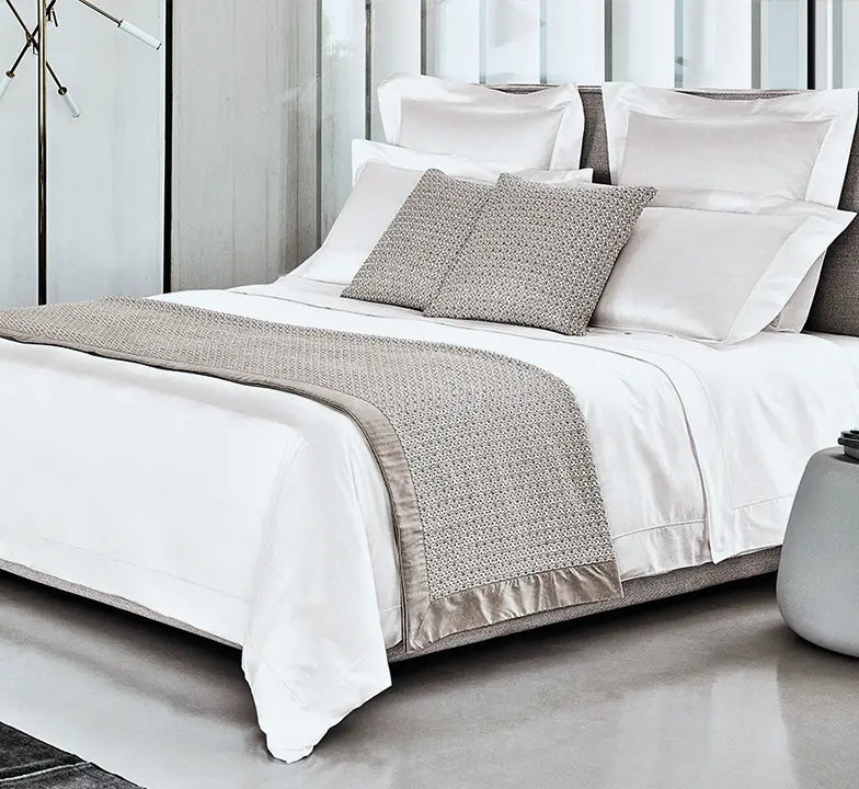 Luxury white bedding set styled with textured beige bed runner and pillows