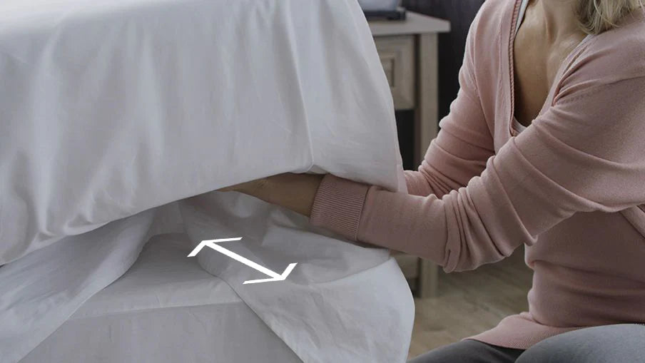 Person tucking a bed sheet under a mattress for a neat fit