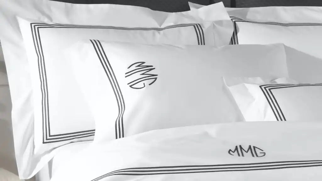 White linen bedding set with black embroidered border and monogram pillow covers