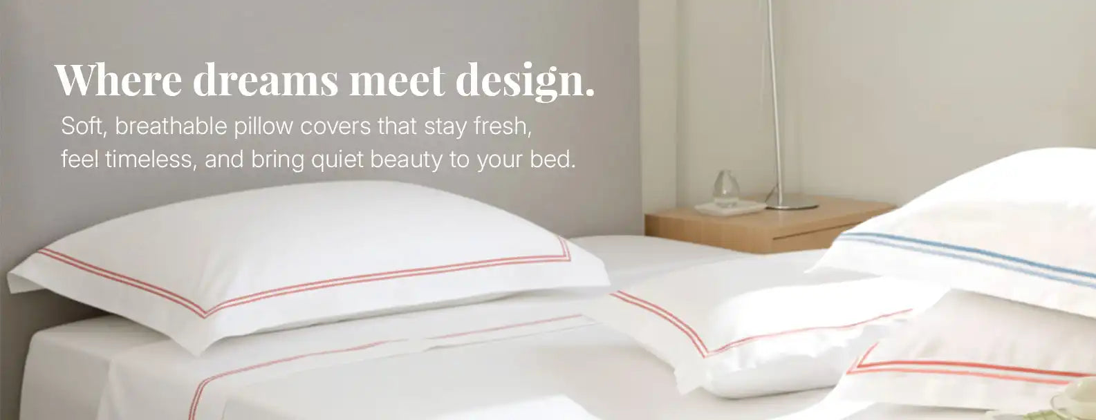 White pillow covers with red and blue border detailing styled on a modern bedroom bed.