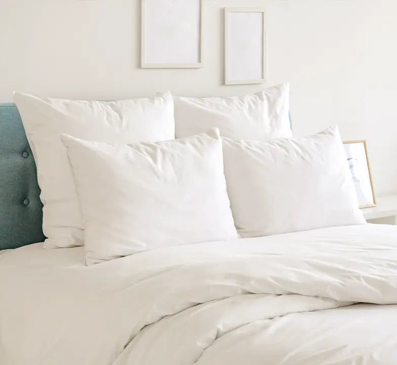 White pillow covers styled on luxury bed with layered white bedding